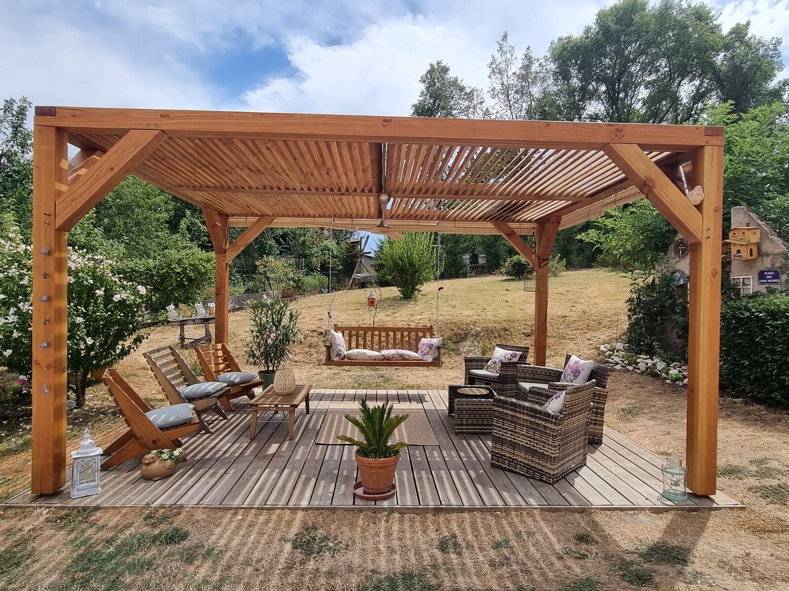 La pergola en bois et sa terrasse, balancelle et salon de jardin